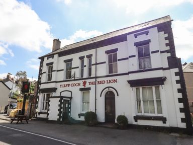 Exterior of a white building with black trim and red signage reading Y Llew Coch The Red Lion
