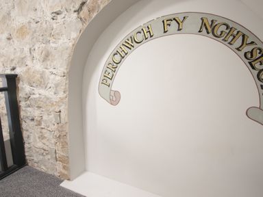 An interior wall with stone on one side and a white arched niche with text at The Sigma Penthouse in Dyserth