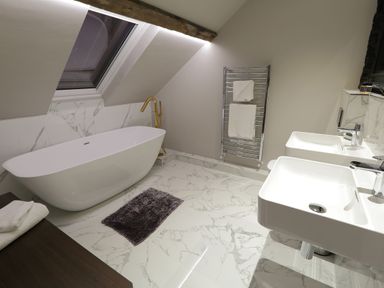 A bathroom with a bathtub a towel rack and two sinks at The Sigma Penthouse in Dyserth