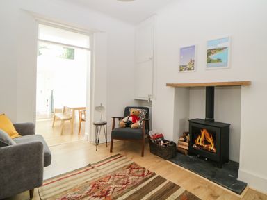 A living room with a fireplace a gray sofa a chair with a teddy bear and a rug at Saltwater Cottage in Babbacombe