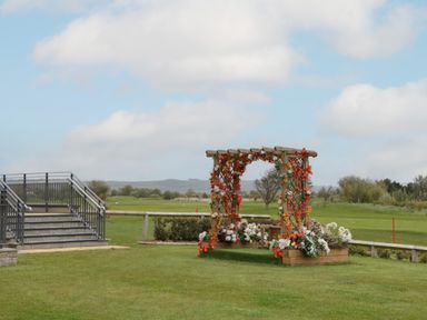 A wooden swing decorated with flowers on a grassy area near metal stairs at 14 Fairways in Burnham-On-Sea