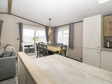 A dining area with a table and chairs near windows with curtains in a living space at 14 Fairways in Burnham On Sea