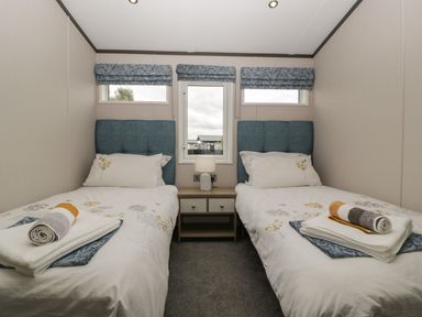 A bedroom with two single beds and a nightstand with a lamp at 14 Fairways in Burnham-On-Sea