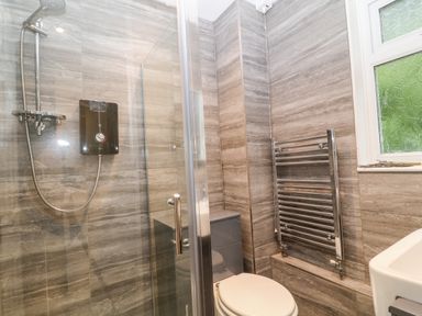 A bathroom with a shower enclosure toilet radiator and window at Lavender Lodge in St Ann's Chapel Cornwall