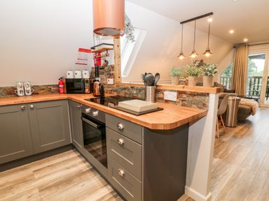 A kitchen with gray cabinets wooden countertops a stove microwave kettle and utensils at Lavender Lodge in St Anns Chapel Cornwall