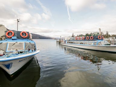Two boats docked on a body of water with hills and trees in the background at Rose Cottage in Burneside