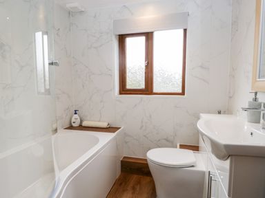A bathroom with a bathtub toilet sink and a window at Rose Cottage in Burneside