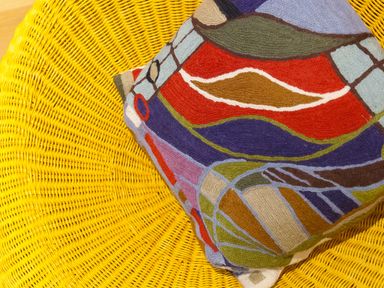 A yellow woven chair with a colorful patterned cushion