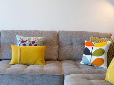 A gray couch with five colorful decorative pillows in a living room at Crystal Bay in St Ives