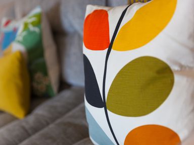 A close up of a cushion with a colorful leaf pattern on a grey sofa at Crystal Bay in St Ives