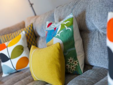 A close up of colorful decorative cushions on a grey fabric sofa at Crystal Bay in St Ives