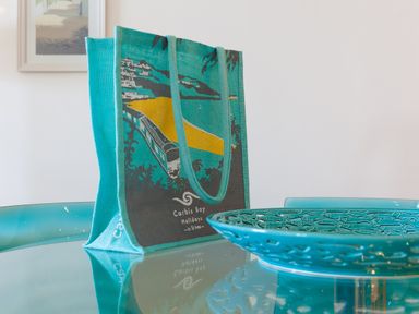 A turquoise tote bag and a decorative plate on a glass table at Crystal Bay in St Ives