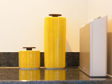 Two yellow containers with white leaf patterns on a black countertop at Crystal Bay in St Ives