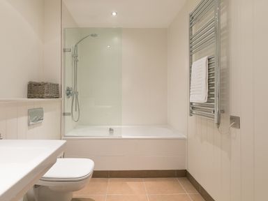 A bathroom with a bathtub shower combination a toilet and a towel radiator at Crystal Bay in St Ives