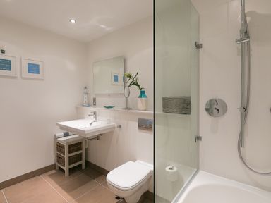 A bathroom with a sink toilet bathtub shower and wall mirror at Crystal Bay in St Ives