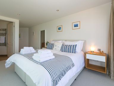 A bedroom with a bed white and striped linens towels on the bed a bedside table with a lamp Crystal Bay St Ives