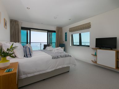 A bedroom with a double bed facing windows overlooking the sea at Crystal Bay in St Ives