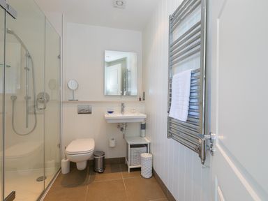 A bathroom with a glass shower enclosure toilet sink mirror and towel rack at Crystal Bay in St Ives
