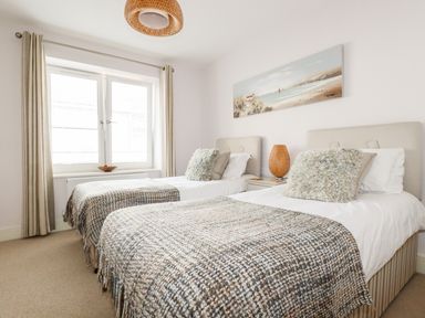 A bedroom with two single beds and a window at 16 Ocean Heights in Newquay