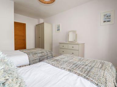 A bedroom with two single beds a wardrobe a chest of drawers and a mirror at 16 Ocean Heights in Newquay