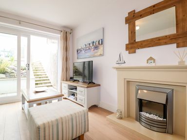 A living room with a fireplace tv and coffee table near sliding glass doors at 16 Ocean Heights in Newquay