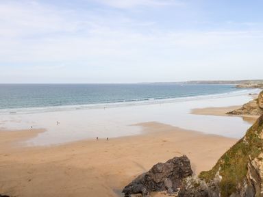 A beach with sand, rocks, and a few people near the water at 16 Ocean Heights in Newquay