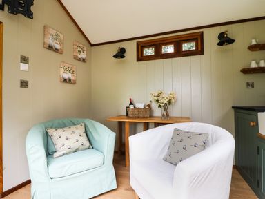 A small living area with two armchairs a wooden table with flowers and a basket on it at Little Silver Pheasant in High Bickington