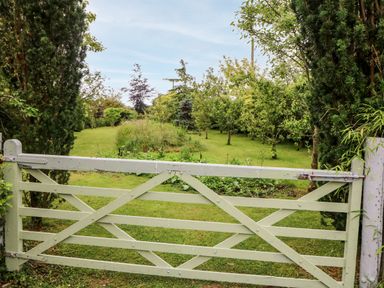 A wooden gate opening to a grassy garden with trees and shrubs at Teach Chiuin Coolaheen near Cappoquin County Waterford