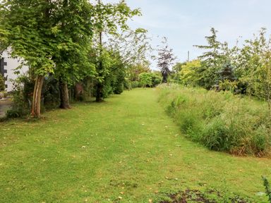 A grassy garden with trees and bushes lining each side at Teach Chiuin in Coolaheen near Cappoquin County Waterford