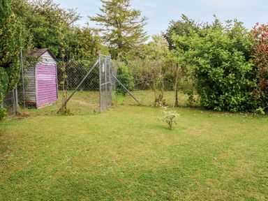 A fenced garden area with a small wooden shed and various bushes at Teach Chiuin Coolaheen near Cappoquin County Waterford