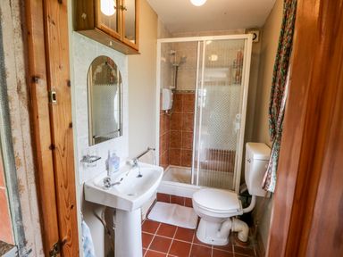 A bathroom with a sink and mirror to the left and a toilet and shower enclosure to the right at Teach Chiuin Coolaheen near Cappoquin County Waterford