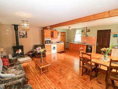 A living room with a wood stove sofa armchair wooden coffee table and dining table with chairs at Teach Chiuin Coolaheen near Cappoquin County Waterford