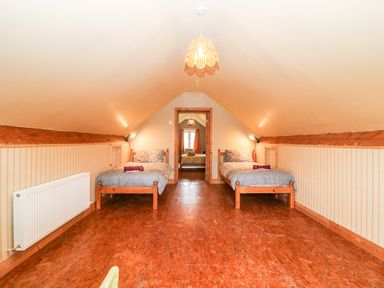 An attic bedroom with two single beds placed on either side and a bed visible through an open doorway at Teach Chiuin in Coolaheen near Cappoquin County Waterford