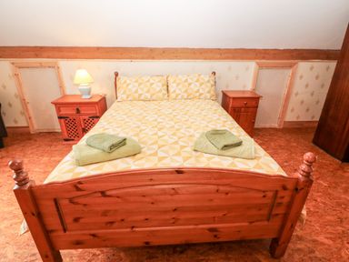 A bedroom with a wooden bed and bedside tables with a lamp and towels at Teach Chiuin in Coolaheen near Cappoquin County Waterford