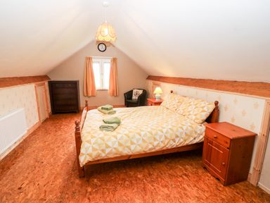 A bedroom with a double bed two bedside tables a chest of drawers a window with curtains and a chair at Teach Chiuin Coolaheen near Cappoquin County Waterford