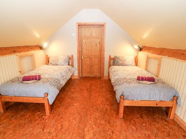 A bedroom with two single beds wooden door and slanted ceiling at Teach Chiuin Coolaheen near Cappoquin County Waterford