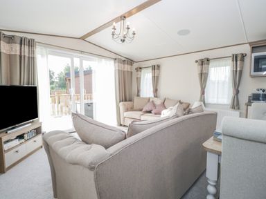 A living room with sofas television and curtains at 22 Sherwood in South Lakeland Leisure Village near Warton