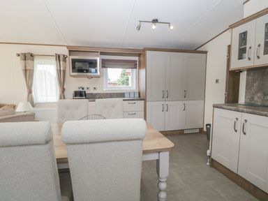 A kitchen and dining area with a wooden table and upholstered chairs at 22 Sherwood South Lakeland Leisure Village near Warton