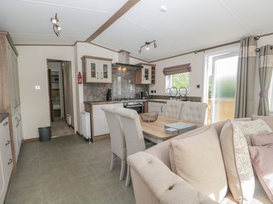 An open kitchen and dining area with beige chairs and wooden table next to a beige sofa at 22 Sherwood South Lakeland Leisure Village near Warton