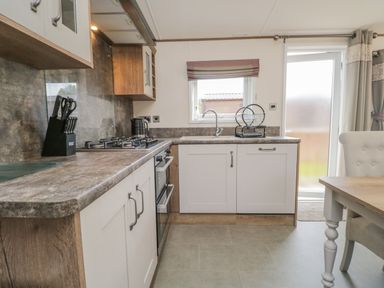 A kitchen with a gas stove knife holder sink and dishwasher at 22 Sherwood South Lakeland Leisure Village near Warton
