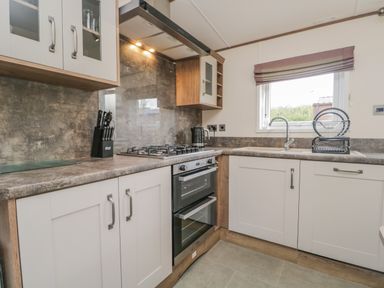 A kitchen with a gas stove oven knife block sink and window at 22 Sherwood South Lakeland Leisure Village near Warton