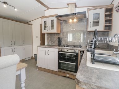 A kitchen with cabinets a stove oven and a dish rack at 22 Sherwood South Lakeland Leisure Village near Warton