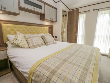A bedroom with a bed with yellow headboard and plaid bedding at 22 Sherwood South Lakeland Leisure Village near Warton