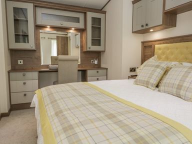 A bedroom with a made bed having plaid pillows and a bed runner with a desk and chair in the background at 22 Sherwood South Lakeland Leisure Village near Warton