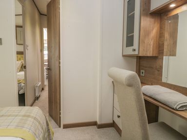 A bedroom with a desk and chair a folded towel on the desk and a doorway leading to another room at 22 Sherwood South Lakeland Leisure Village near Warton