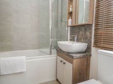 A bathroom with a bathtub shower combination a sink with cabinet and a toilet in 22 Sherwood South Lakeland Leisure Village near Warton
