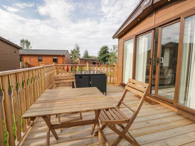 A wooden deck with a table and chairs outside a cabin at 22 Sherwood South Lakeland Leisure Village near Warton