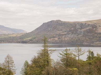 A lake with trees in the foreground and hills in the background at Derwent Haven in Keswick
