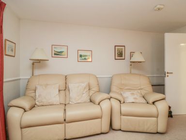 A living room with two leather sofas and paintings on the wall at Derwent Haven in Keswick