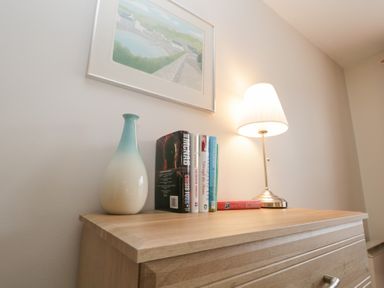A living room with a lamp and books on a chest of drawers at Derwent Haven in Keswick